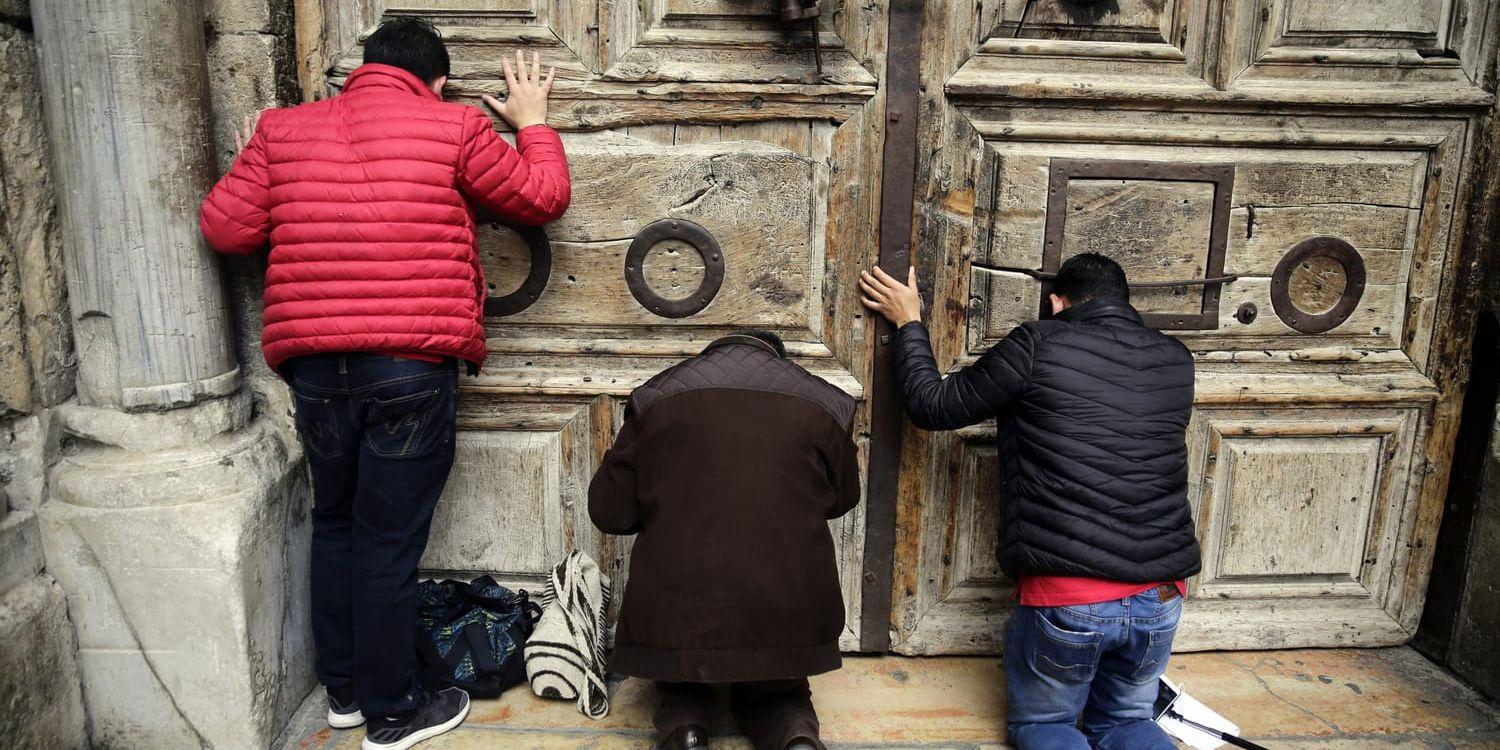 Besökare böjer knä och ber framför den Heliga gravens kyrka i Jerusalem medan den hölls stängd. På tisdagskvällen kom beskedet att den öppnar igen.