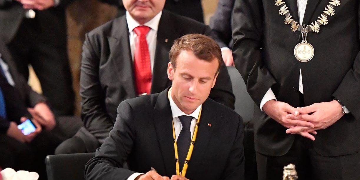 Frankrikes president Emmanuel Macron skriver i den gyllene boken i Aachens stadshus i samband med utdelningen av Karlspriset. I bakgrunden syns Ukrainas president Petro Porosjenko.