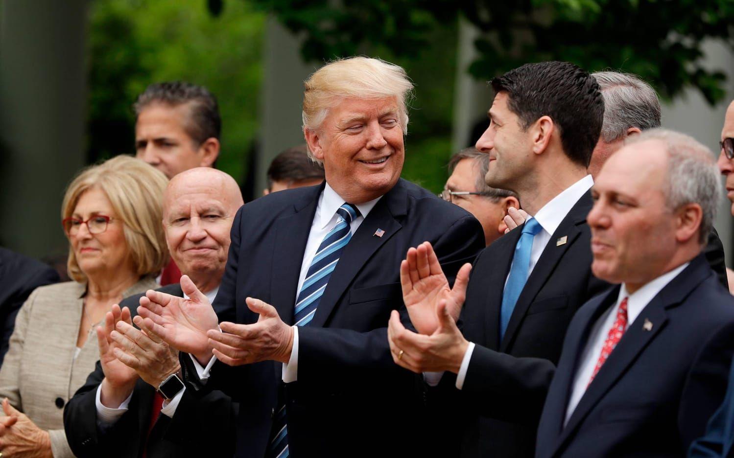 President Donald Trump, omgiven av representanthusets ledande Republikaner, firar framgången i Vita husets Rosenträdgård.
