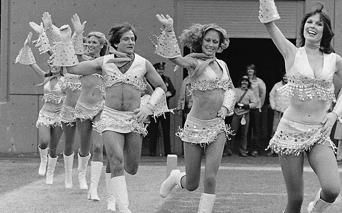 Robin Williams tar på sig en av cheerleader-gruppen Broncos' Pony Express outfits och sluter upp med cheerleader-tjejerna vid filmningen av en TV-serie 1979. Bild TT