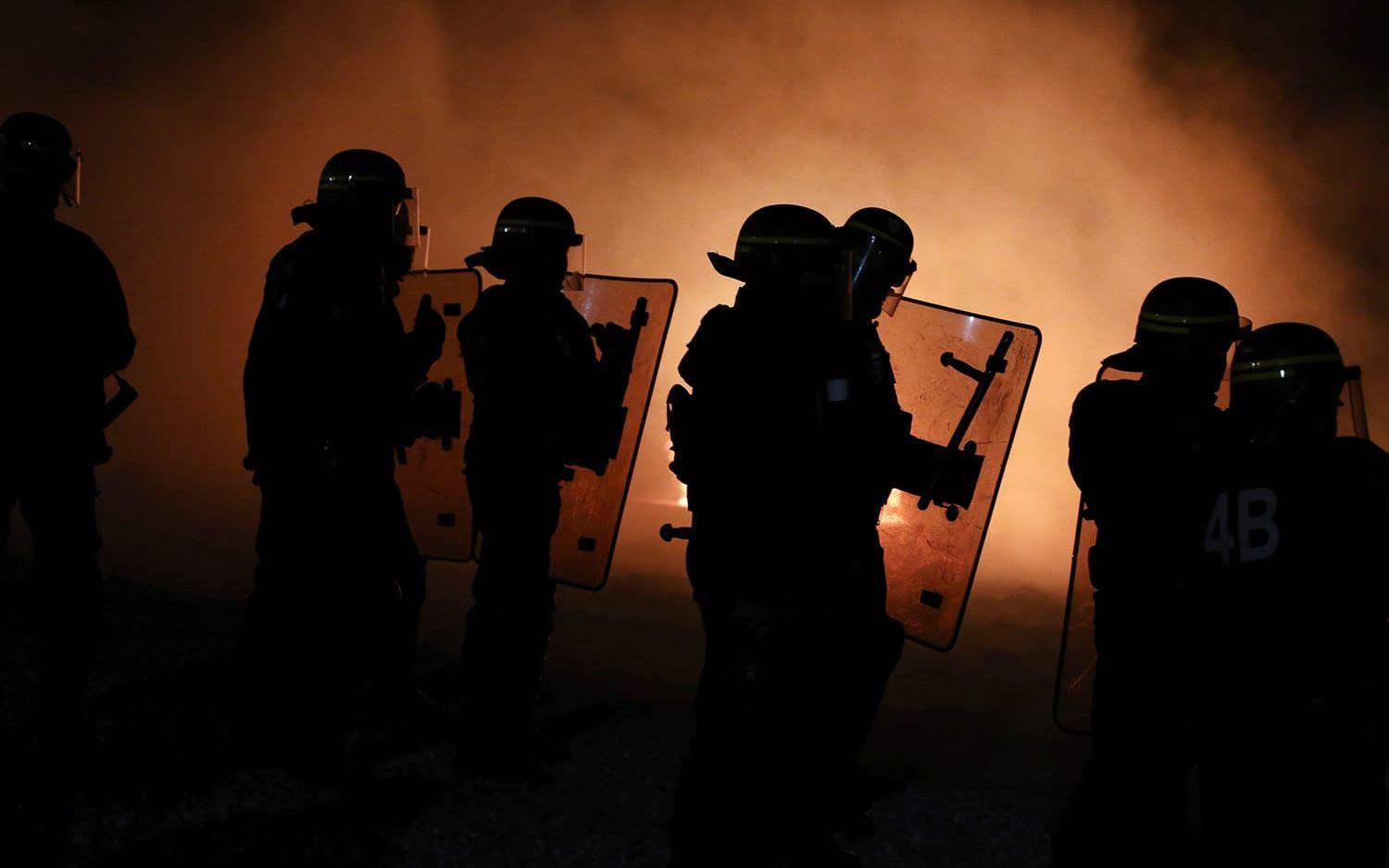 Kravallpolis under en aktion i Djungeln under den sena söndagskvällen. Under måndagen har evakueringen av jättlägret inletts. Foto: AP