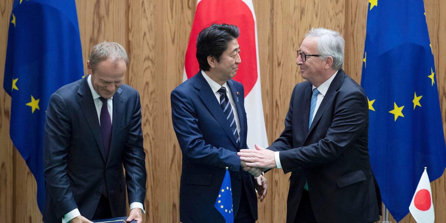Japans premiärminister Shinzo Abe, i mitten, skakar hand med EU-kommiussionens ordförande Jean-Claude Junker efter att ha skrivit under frihandelsavtalet på tisdagen.