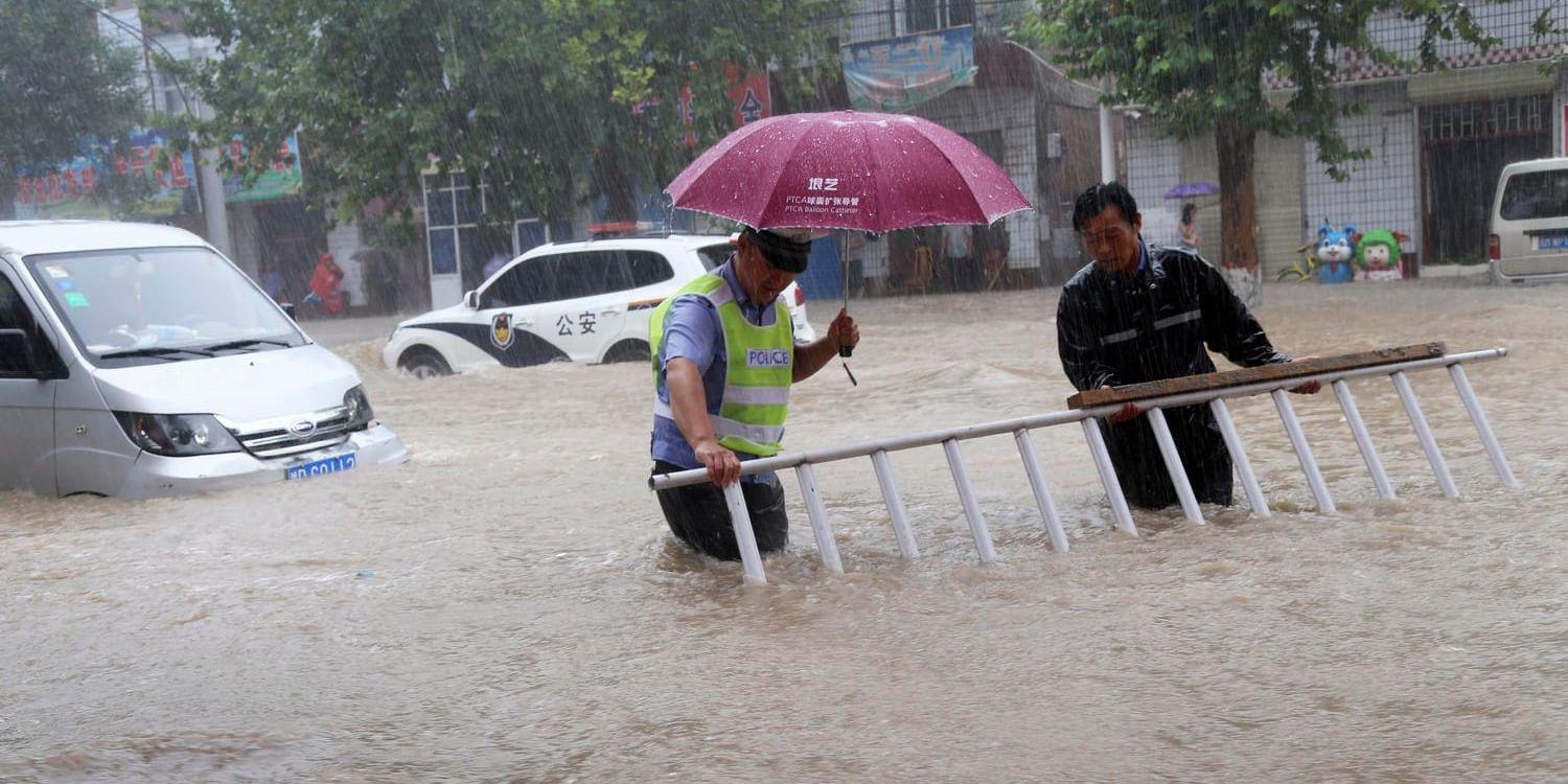 En man hjälper en trafikpolis på en översvämmad väg i Wanrong i Shanxiprovinsen i norra Kina.