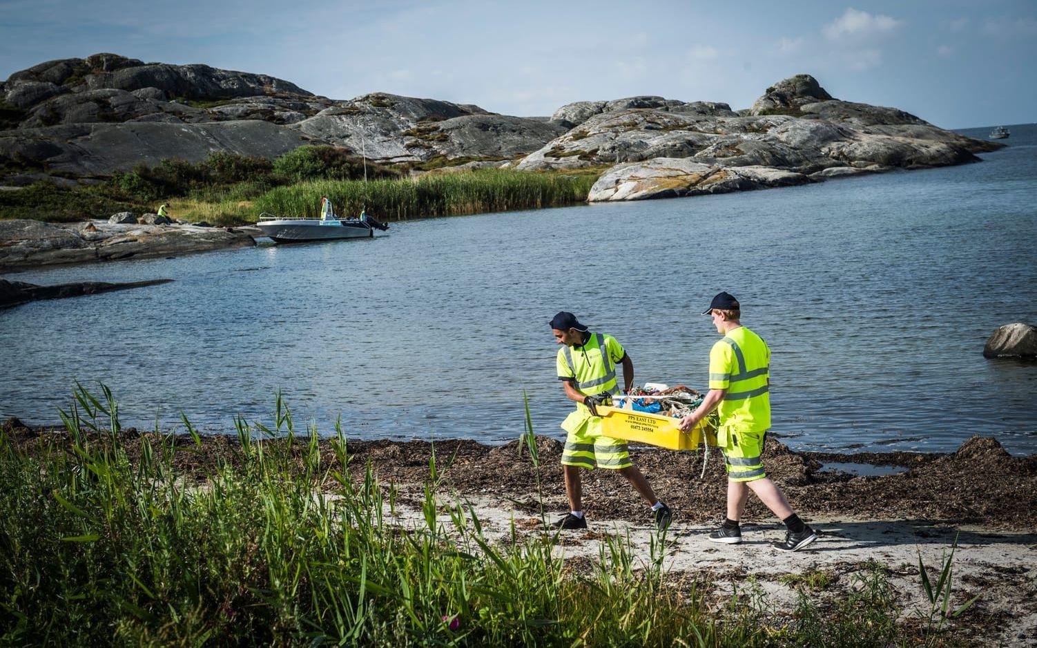Mena Kourie och William Eklund bär en fiskelåda i plast med brittisk märkning till båten. Bild: Olof Ohlsson
