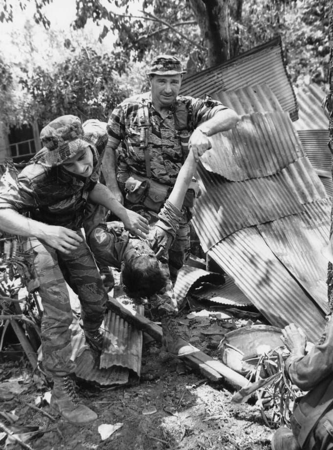 Amerikanska soldater bär en sydvietnamesisk soldat i säkerhet efter att denne sårats i strider mot FNL-förband i Saigon under Tetoffensiven, 17 juni 1968. Arkivbild
