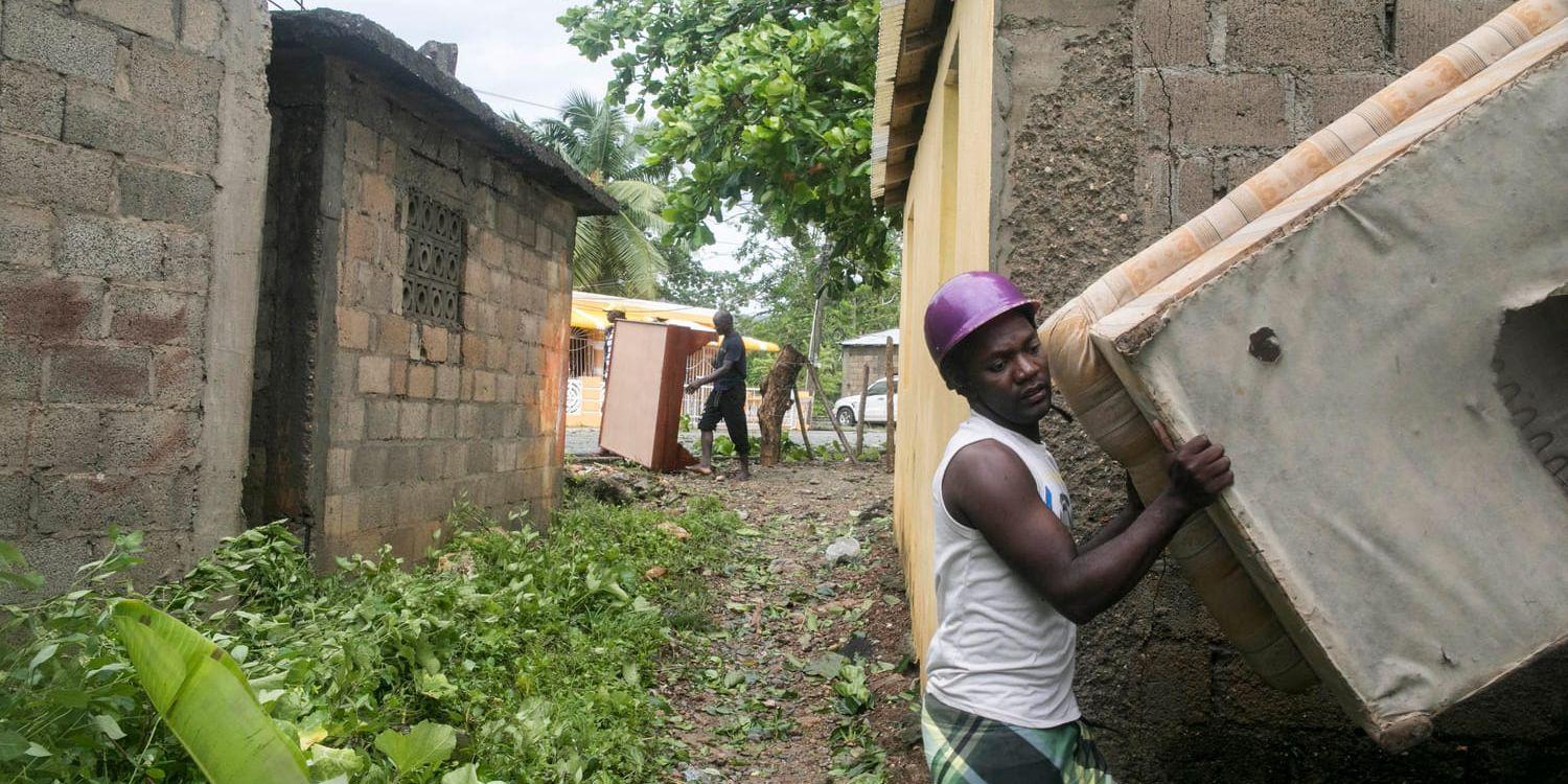 Grannar flyttar ut möbler ur ett översvämmat hus i Samana, Dominikanska republiken.