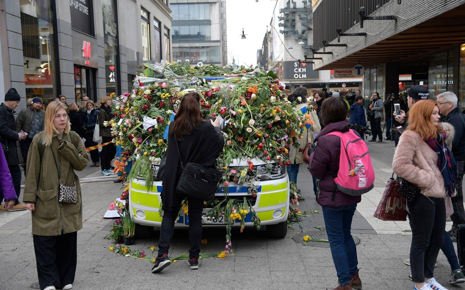 En polisbil på Drottninggatan täcktes med blommor någon dag efter dådet. Foto: TT