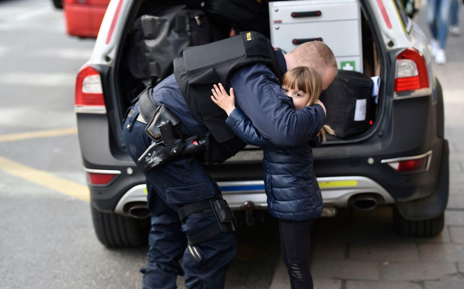 Stockholm den 9 april. En liten flicka ger en polisman en kram. M‰nniskor samlades vid Åhléns City i centrala Stockholm för att hedra offren för terrorattacken på Drottninggatan. Foto: Noella Johansson