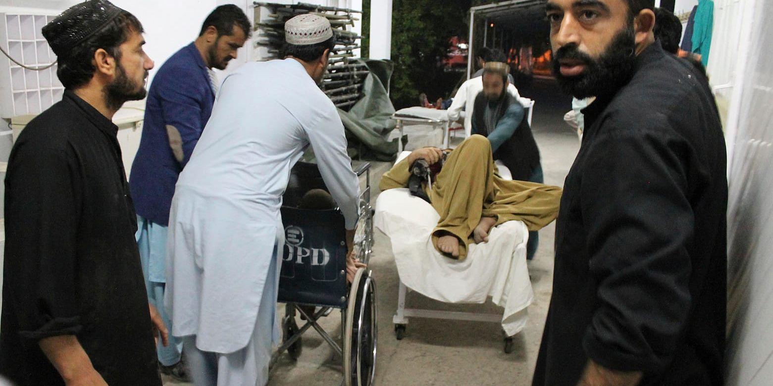 En skadad man får hjälp efter det dödliga dådet vid en idrottsarena i den oroliga provinsen Helmand i Afghanistan.
