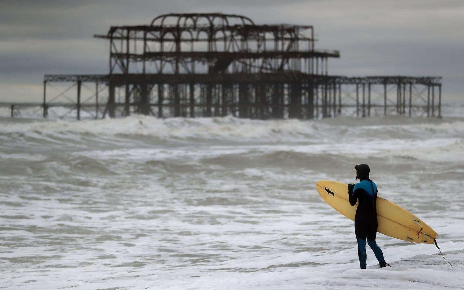 En är på väg ut i vågorna som stormen Angus piskar upp vid West Pier i Brighton i sydöstra England. FOTO: Andrew Matthews/PA 