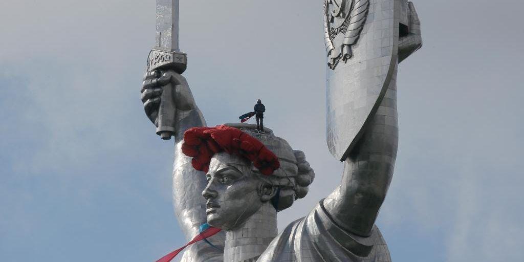 En arbetare placerar en krans på det 102 meter höga "moderlandsmonumentet" i Kiev, på årsdagen av segern över nazisterna i andra världskriget. Men ny lagstiftning gör att monumentet nu kan bli olagligt, eftersom kommunistsymbolerna hammaren och skäran syns på skölden. ARKIVBILD