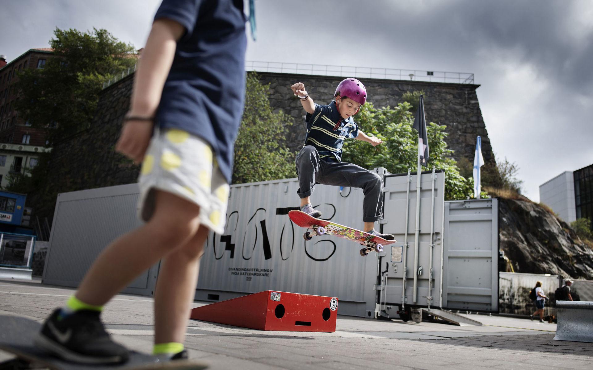 Jim Foufas, gör en frontside 180, Finn Baude, 5 år, i förgrunden. Skateutställning på Esperantoplatsen i Göteborg av Robin Aron.
