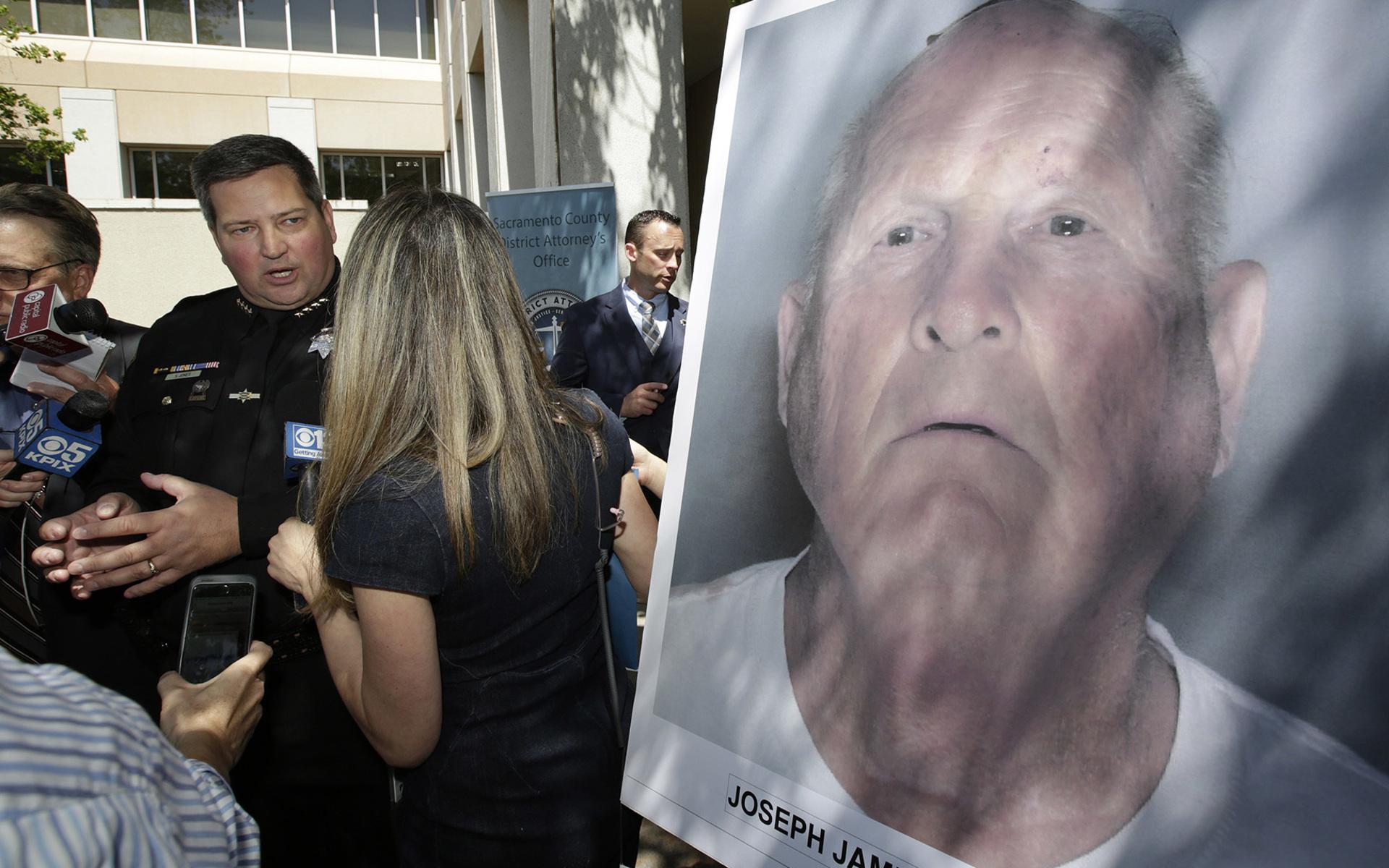 Sacramento Countys sheriff Scott Jones pratar med reportrar om gripandet av Joesph James DeAngelo, som är på fotot i förgrunden. DeAngelo, en före detta polis, knyts via dna-bevis till en rad mord, våldtäkter och inbrott under 70- och 80-talet. FOTO: AP