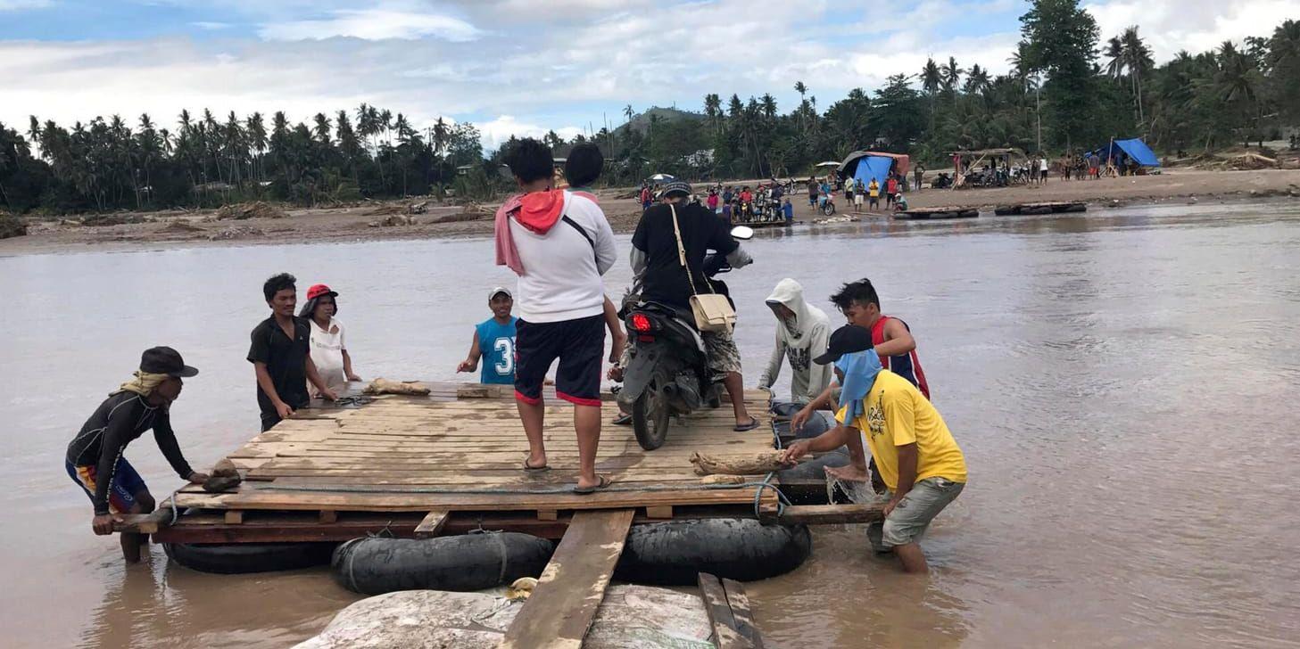 En tillfällig flotte används som transport efter att stormen Tembin förstört en bro i södra Filippinerna.