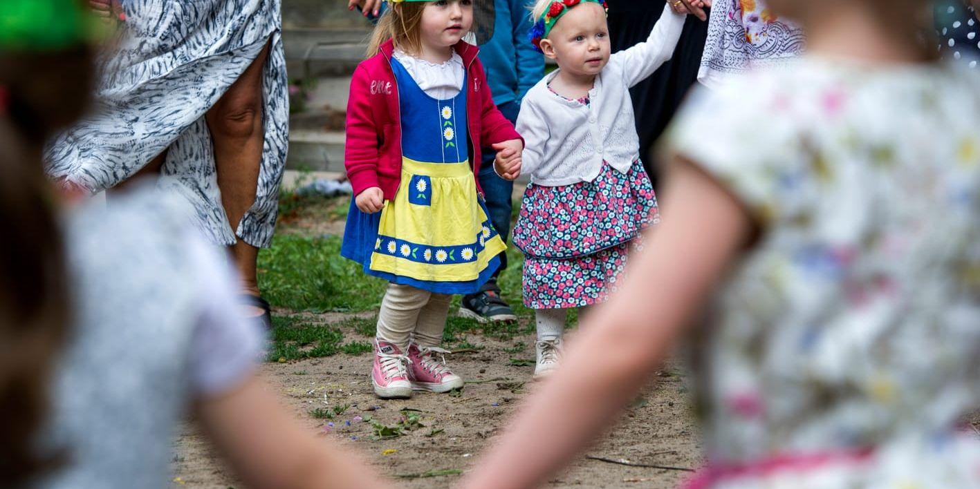 Lillith Lamkén och Julie Ljungberg dansar runt stången under midsommarfirandet på förskolan.