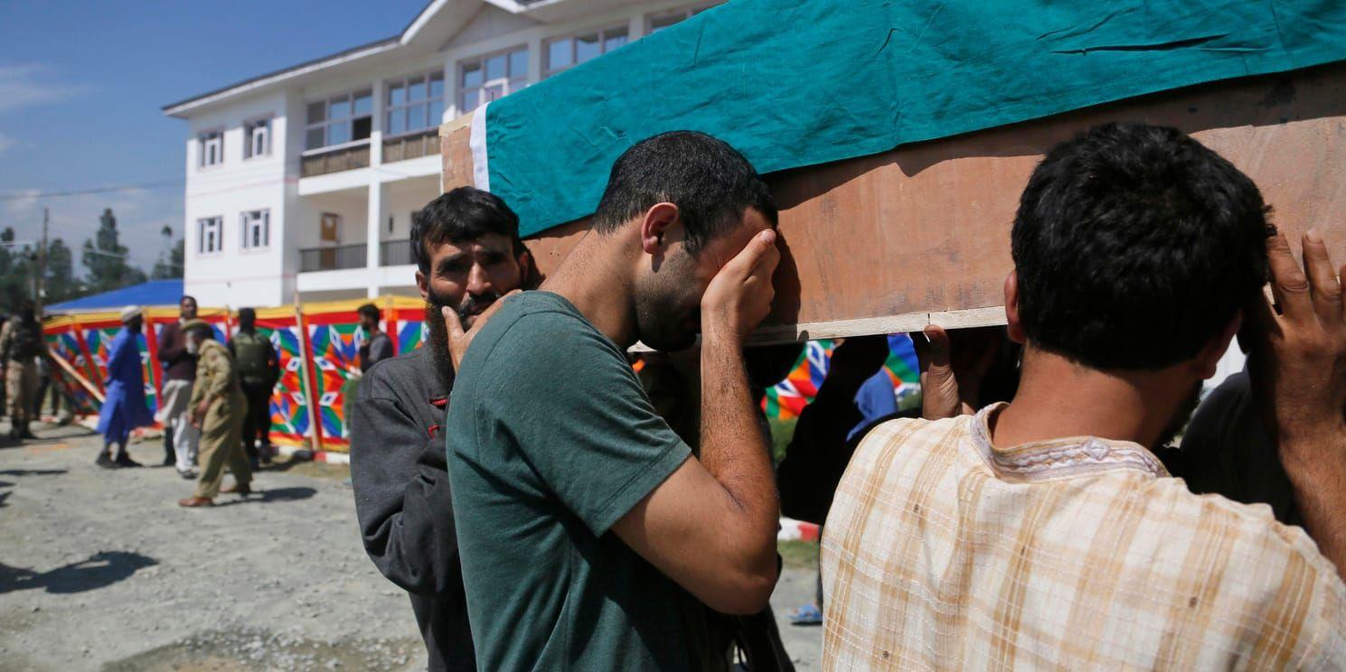 En anhörig till en av de dödade poliserna i indiska Kashmir gråter medan han bär kistan.