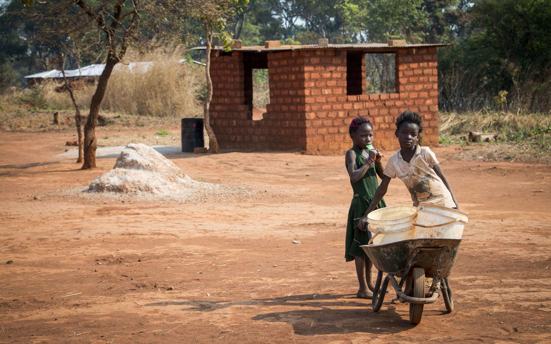 Några flickor är på väg för att hämta vatten i den nya stadsdelen fem kilometer utanför staden Kalumbila. I husen finns varken vatten eller el, det är ont om jobb och odlingsmarken är begränsad.