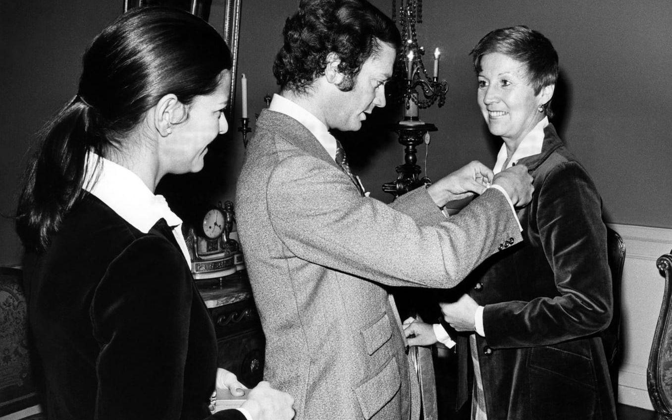 Från vänster drottning Silvia, kung Carl Gustaf och operasångerskan Kjerstin Dellert som tar emot en medalj av kungen (1976)..