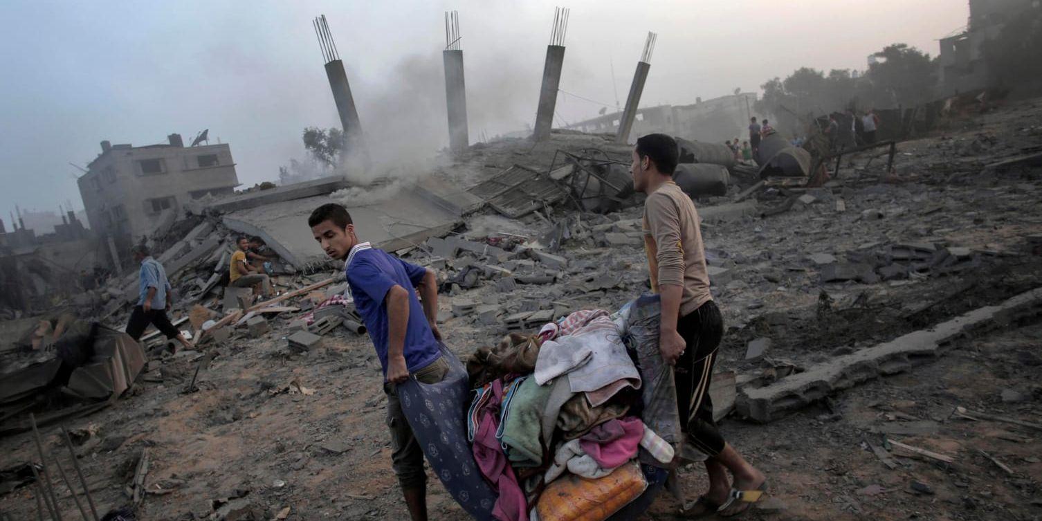 Palestinier bär bort saker från ett söndersprängt hus efter israelisk militär bombat mål på Gazaremsan under tisdagen.