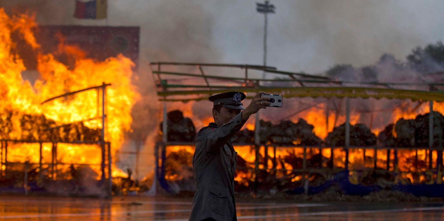 En polis i Myanmar (tidigare Burma) tar en selfie i samband med att de bränner beslagtagen narkotika. Arkivbild.