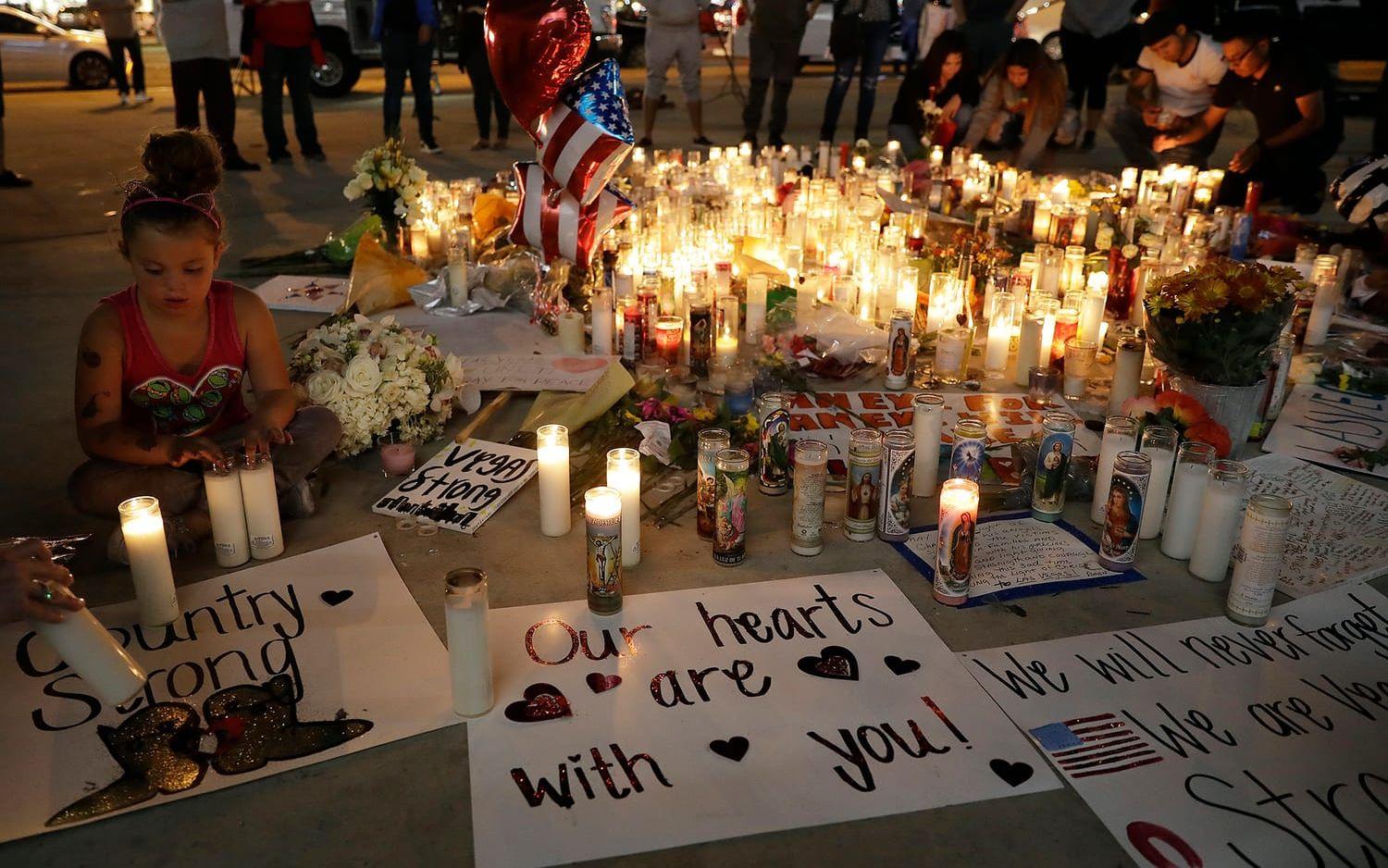 En flicka placerar ett ljus vid en improviserad minnesplats efter massmordet i Las Vegas. FOTO: Marcio Jose Sanchez/AP
