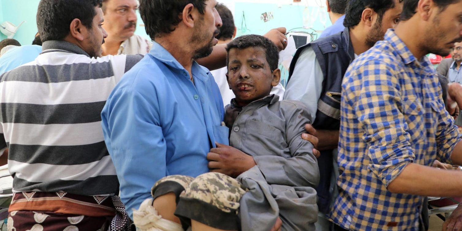 En man bär i väg en pojke som skadades i ett flygangrepp mot en buss i staden Dahyan i provinsen Saada.