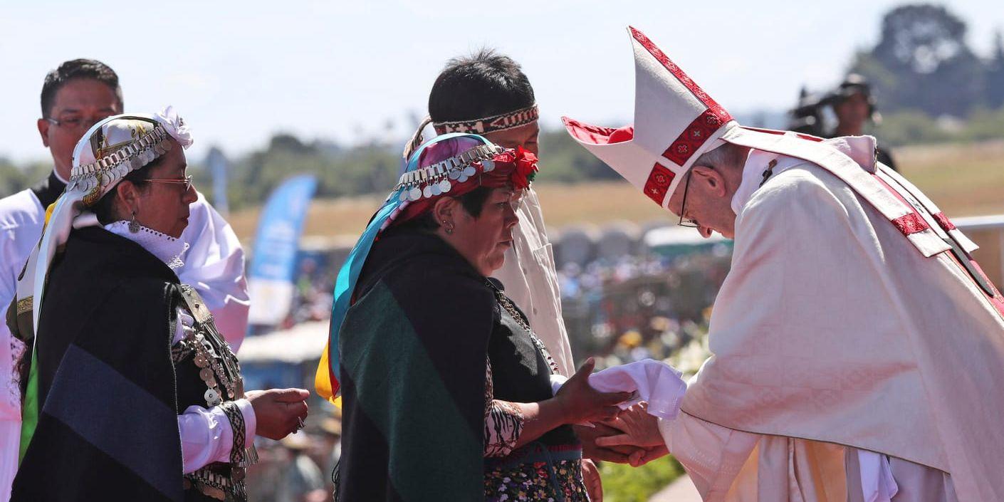 Påven Franciskus tar emot gåvor från en kvinna ut folkgruppen mapuche under en utomhusmässa i södra Chile.