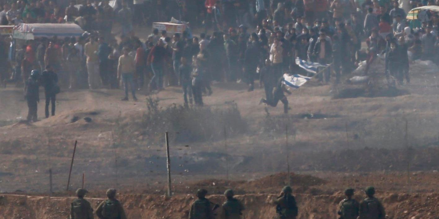 Israeliska soldater framför palestinska demonstranter vid gränsen mot Gaza förra fredagen. Arkivbild.