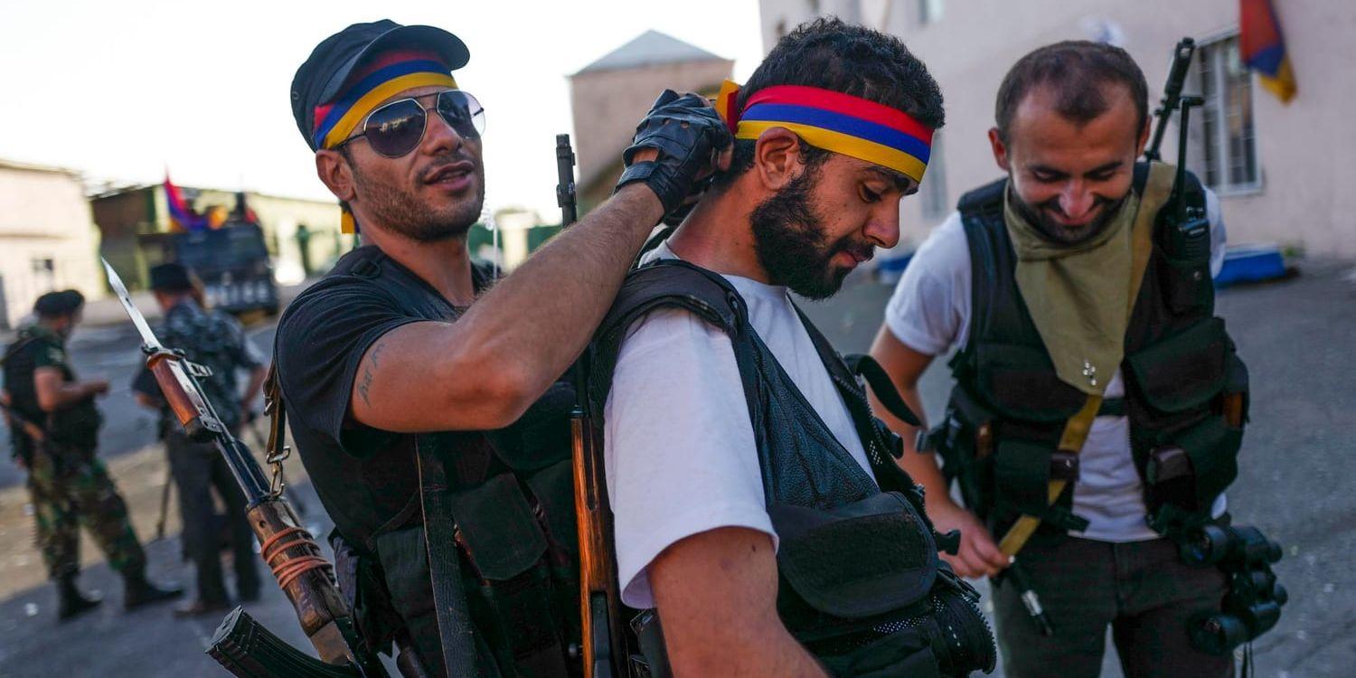 En beväpnad man knyter ett band i den armeniska flaggans färger runt en väns huvud samtidigt som de bevakar en belägrad polisstation i Armeniens huvudstad Jerevan. Under lördagen släpptes de sista ur gisslan, men männen vägrar lägga ner vapnen.