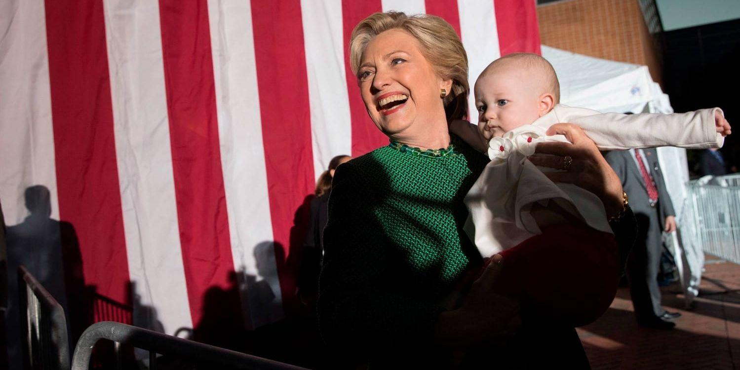 Demokraternas presidentkandidat Hillary Clinton håller i en bebis när hon kampanjar i Charlotte i vågmästarstaten North Carolina.