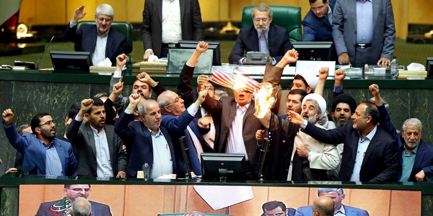 Iranska parlamentsledamöter bränner två pappersark som föreställer den amerikanska flaggan och kärnenergiavtalet, samtidigt som de sjunger antiamerikanska sånger i parlamentet i Teheran.