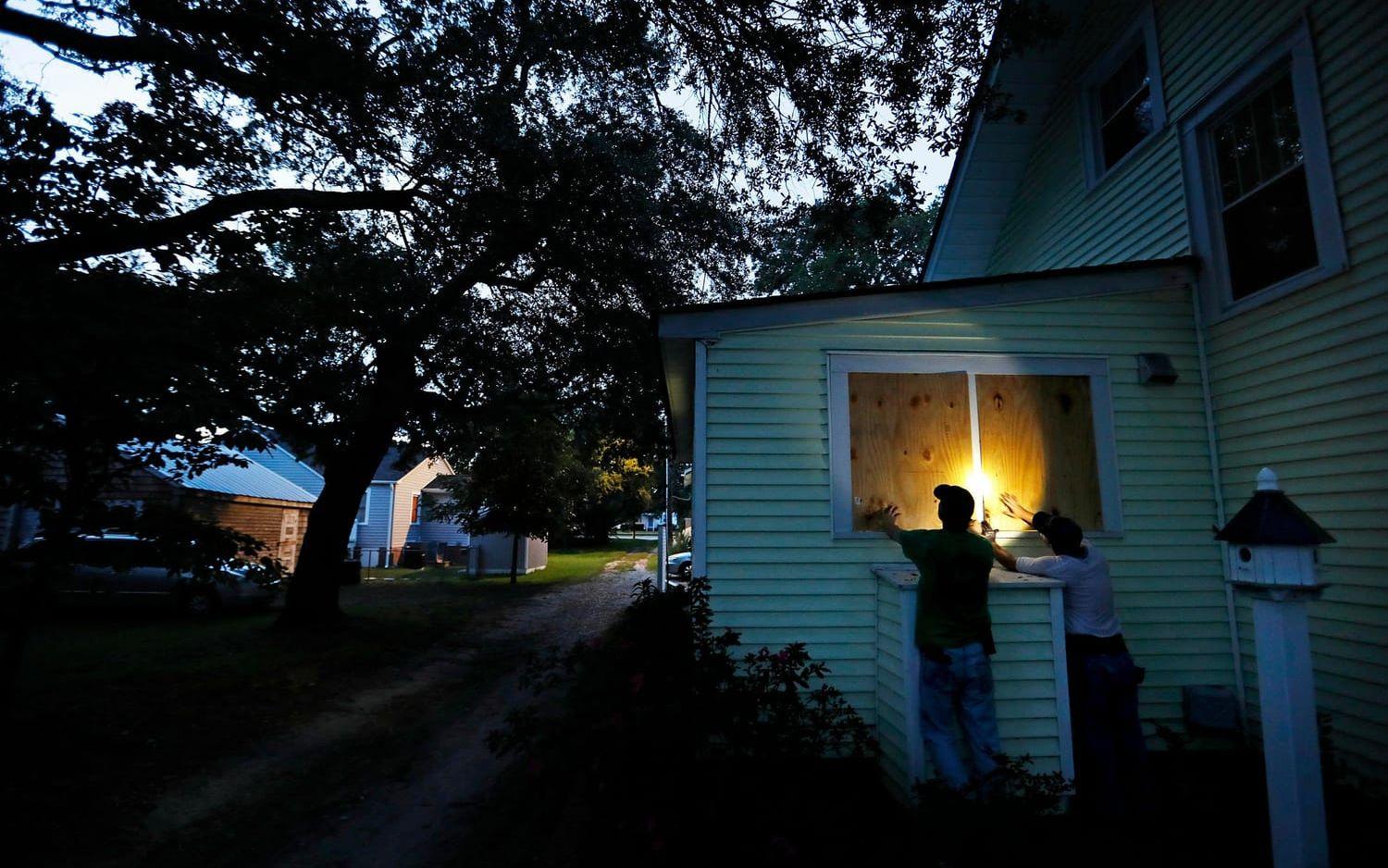 Grannarna Russell Meadows och Rob Muller hjälps åt att spika igen fönster i North Carolina inför &quot;Florence&quot;.