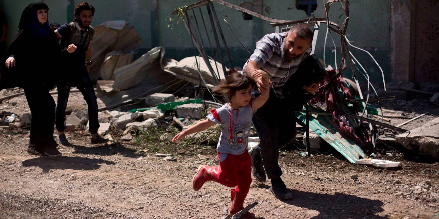 En man flyr undan med sin dotter när irakiska specialstyrkor strider mot Islamiska staten i västra Mosul i maj i år. Arkivbild.