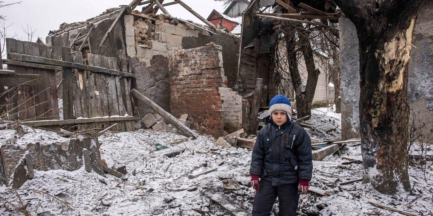 En åttaårig pojke står framför sitt förstörda hus i östra Ukraina. Arkivbild.