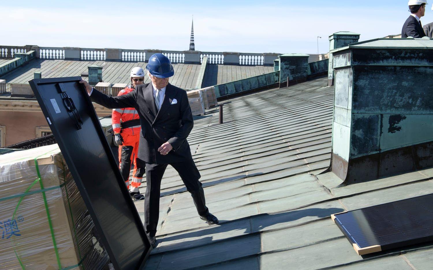 Här hjälper kung Carl XVI Gustaf till att installera solcellspaneler på slottstaket.