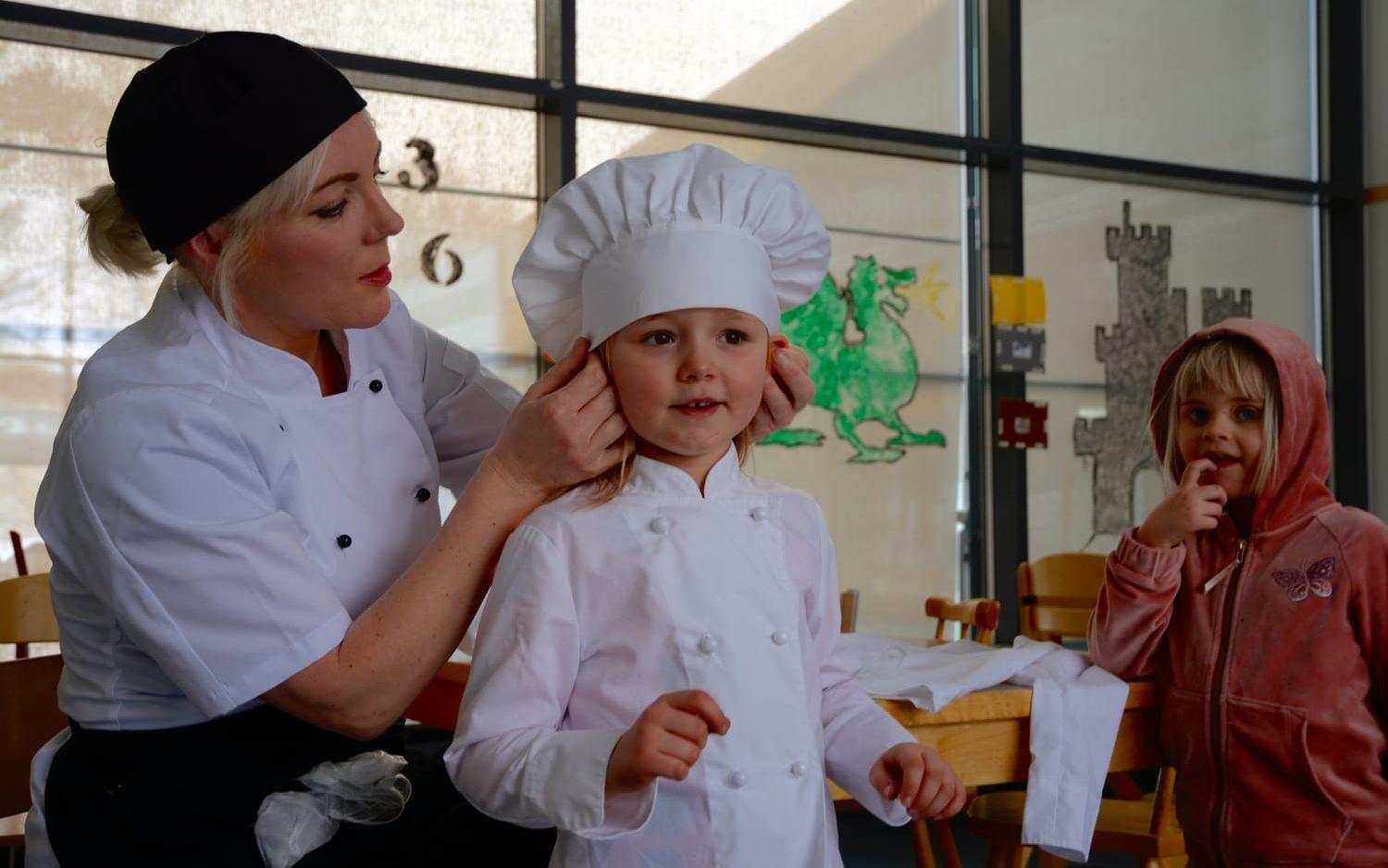 Skolan har köpt in kockkläder i rätt storlekar till barnen i förskolan. Dorotea Bollgård sätter mössan rätt. Bild: Karina Hansson