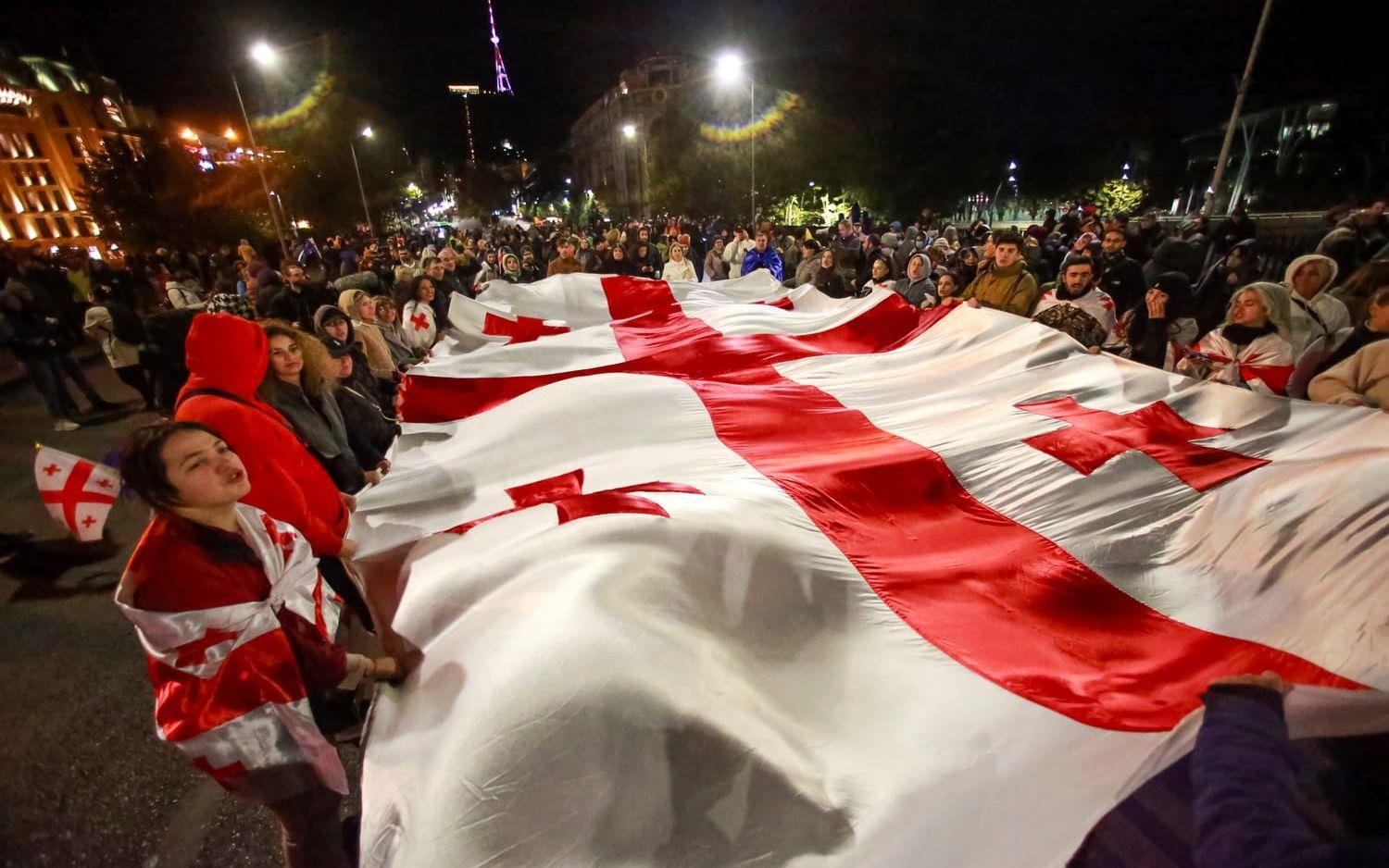 Demonstranter i Tbilisi bär en georgisk flagga under måndagens protester mot valet den 26 oktober.