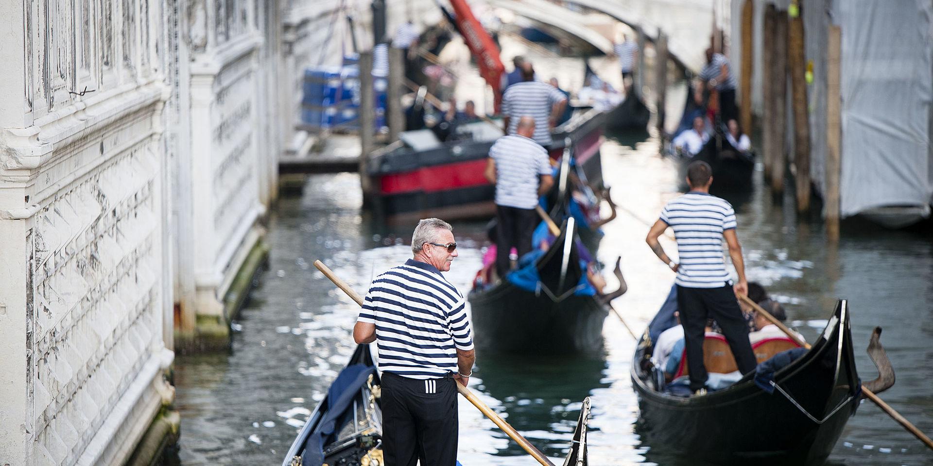 Trafikstockning. Kanalerna är Venedigs gator och transportleder. Gondolerna med turister får snällt lämna plats när en lastbåt måste fram.