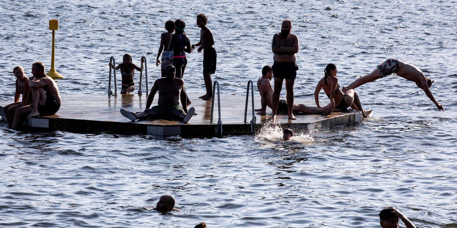 Människor som badar vid Tantolundens badplats i Stockholm i det varma julivädret.