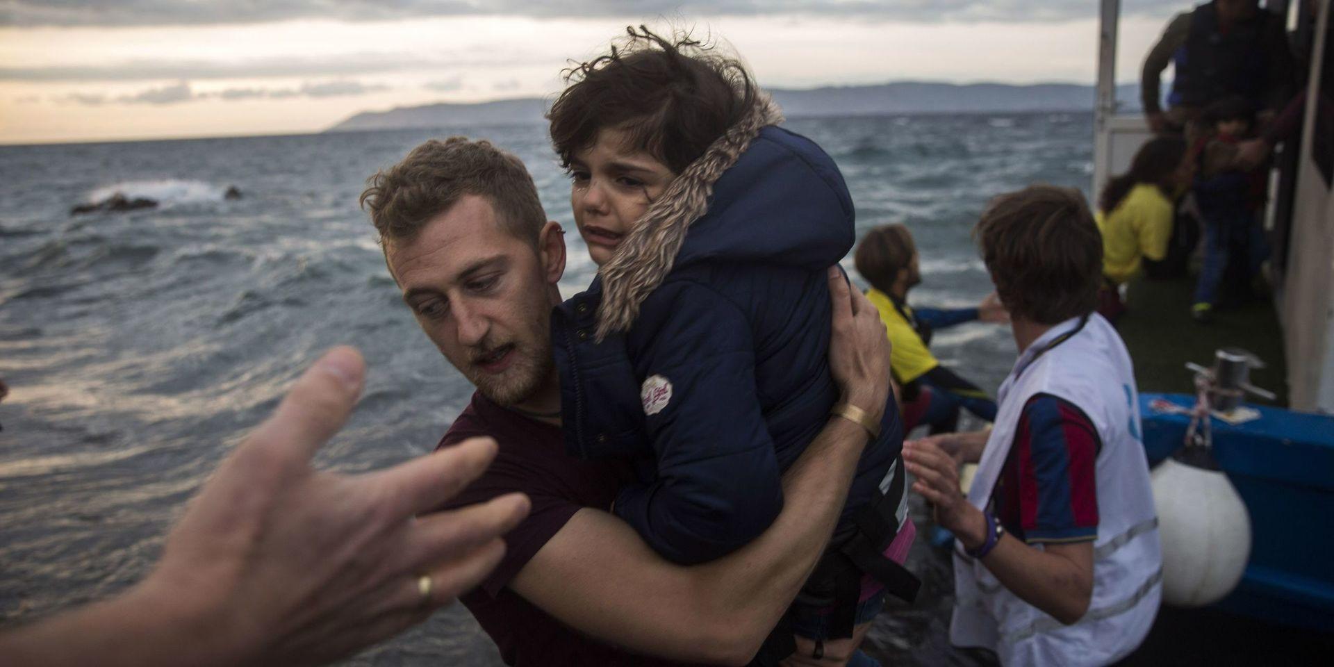 En fotograf hjälper en flykting i land på den grekiska ön Lesbos under flyktingkrisen 2015.