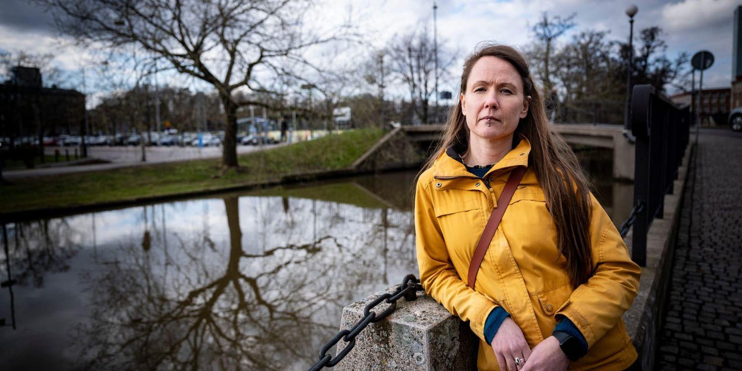 Kvinna med gul jacka lutar sig mot en pelare intill en kanal.