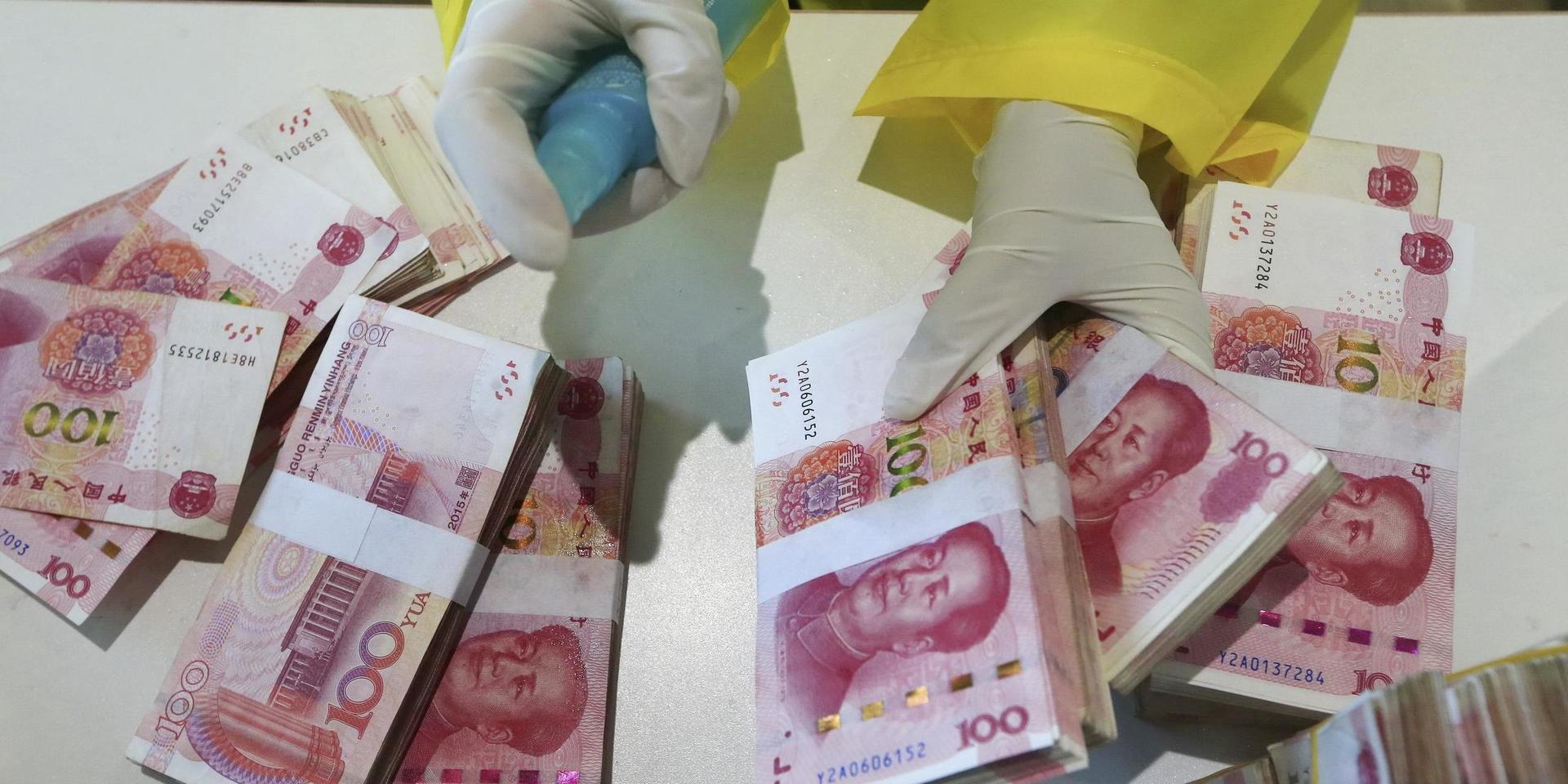 En bankanställd i Sichuanprovinsen, i sydvästra Kina, desinficerar sedlar. Landets ekonomiska återhämtning efter pandemin går som tåget. Arkivbild.