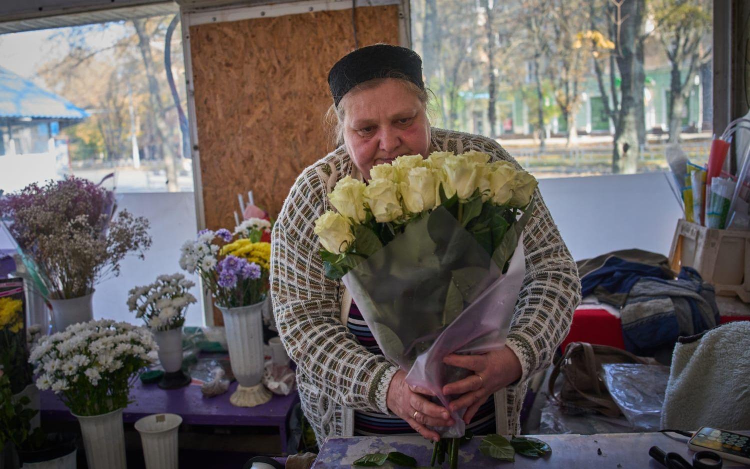 Floristen Olha Komanytska håller igång sin butik i Cherson. Hon berättar att ett stort skott precis missade henne och slog ett stort hål i kioskens vägg, som hon sedan har täckt över.