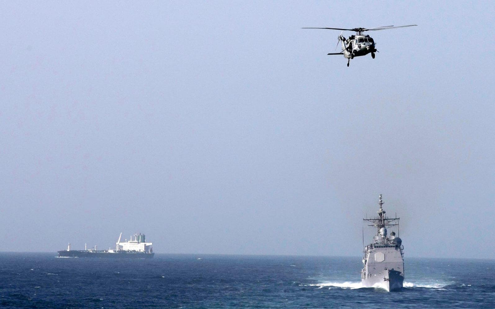 En amerikansk kryssare och en helikopter på en bild tagen från hangarfartyget USS Abraham Lincoln i Persiska viken. Arkivbild.