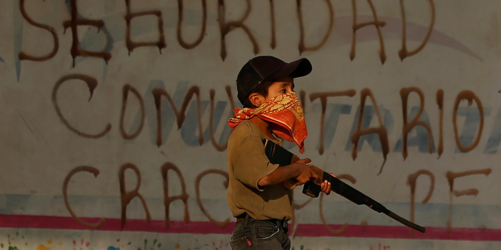 Ett barn övar med sitt leksaksgevär. Byn Ayahualtempa i delstaten Guerrero – en av de mest våldsdrabbade delstaterna i hela Mexiko – hotas av framför allt två lokala knarkgäng: Los ardillos och Los rojos.