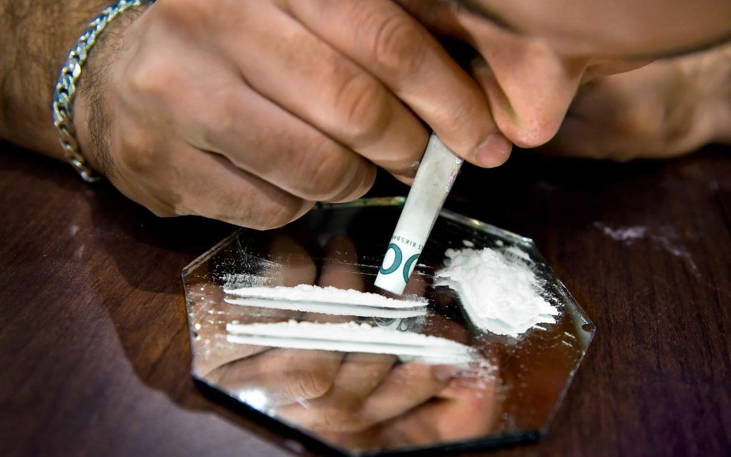 
En man snortar en lina kokain i näsan med hjälp av en hoprullad sedel. Arkivbild.