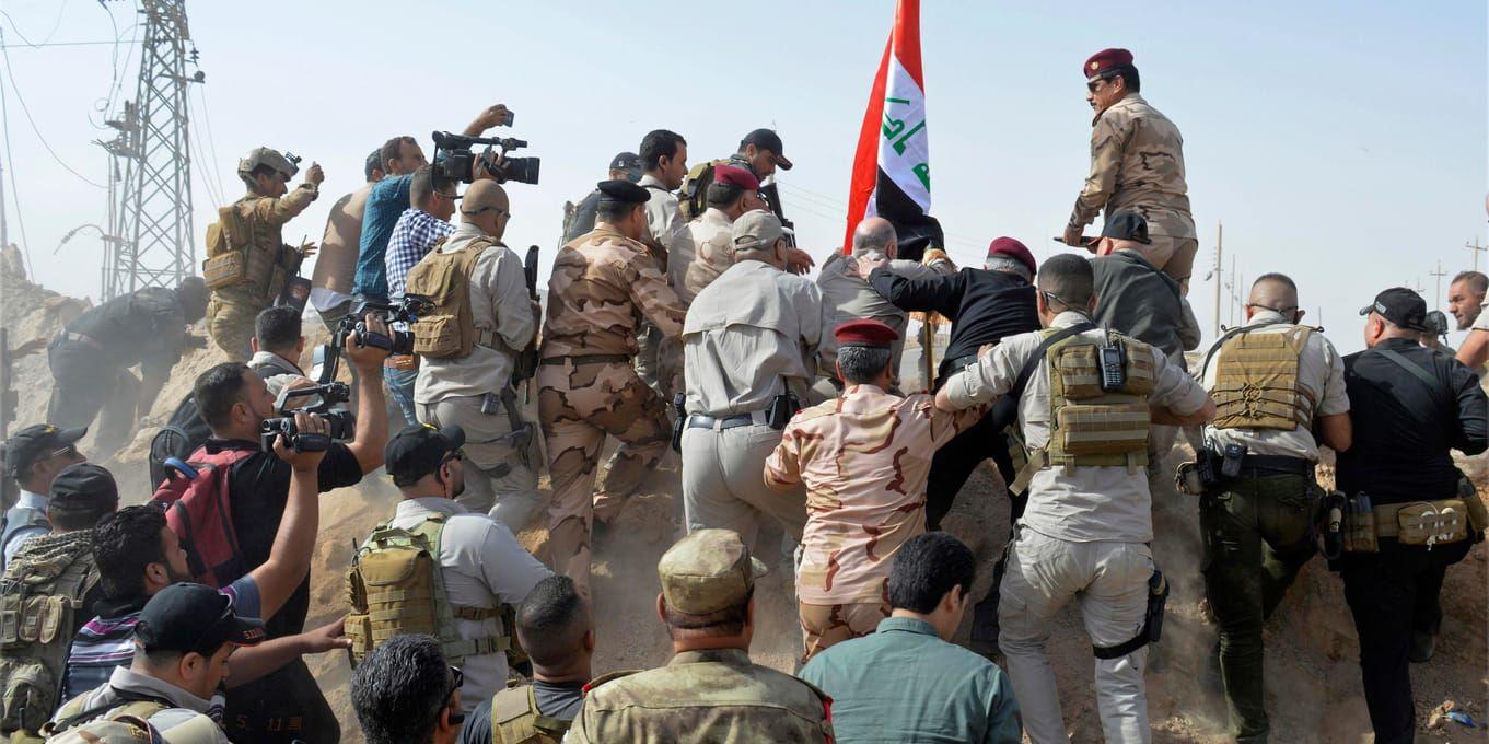 Iraks premiärminister Haider al-Abadi reser den irakiska flaggan i gränsstaden al-Qaim, som nyligen återtagits från IS.