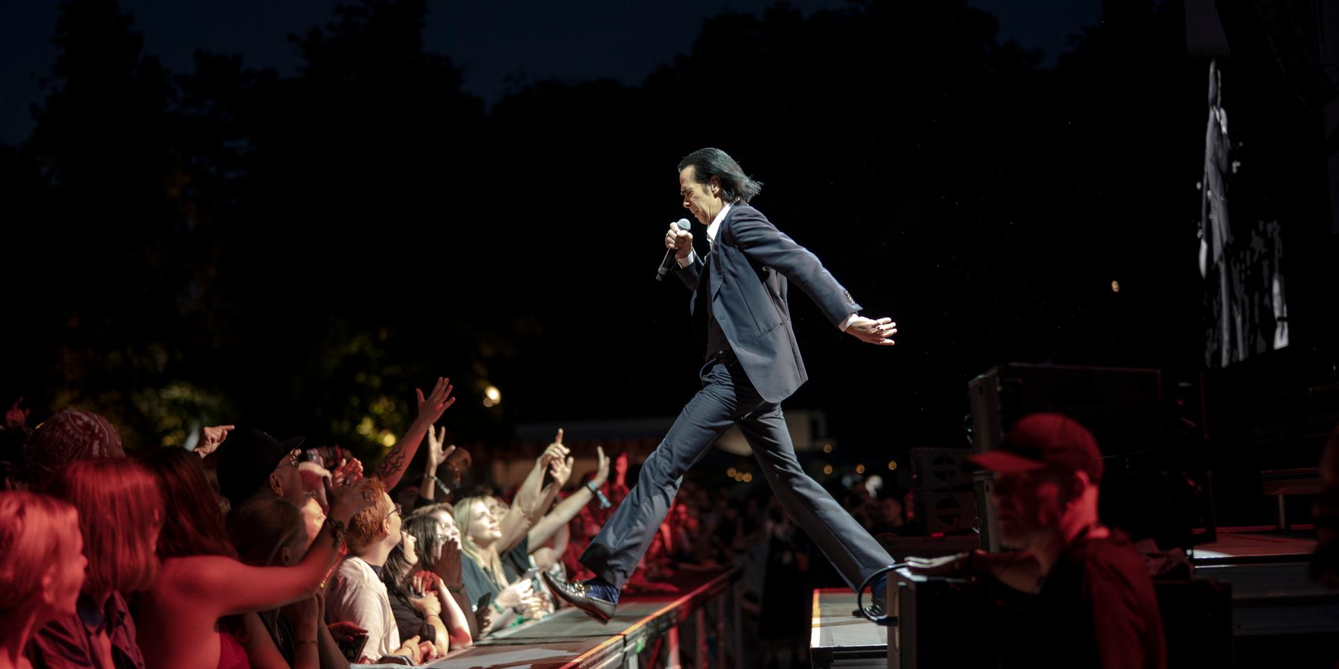 Nick Cave tar ett kliv ut mot publiken.