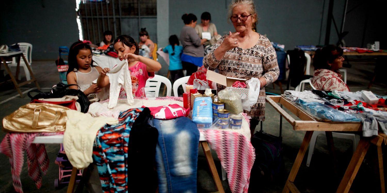 Lucia de Leon och hennes barnbarn Abril och Pricilla sorterar kläder och andra prylar de vill byta bort på en marknad i utkanten av Buenos Aires.
