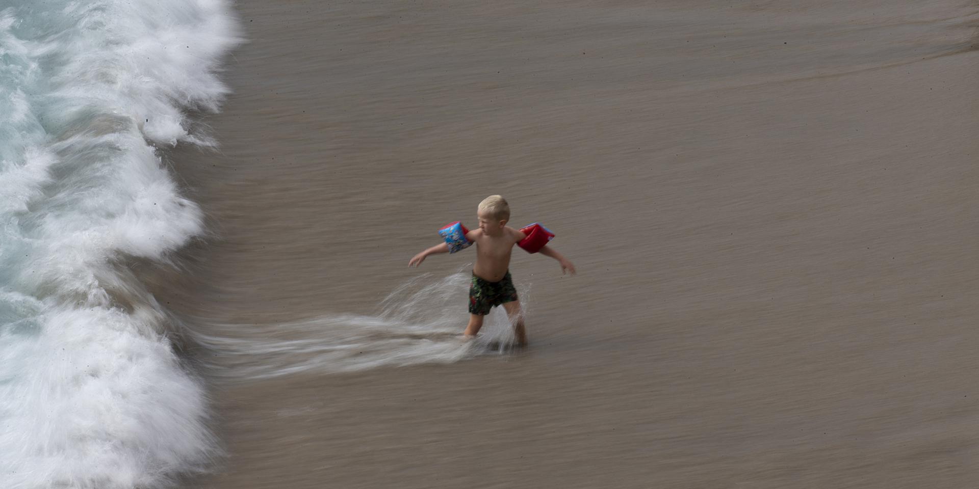 Ett barn leker i vågorna på en strand i Spanien – dock inte i Zahara de los Atunes. Arkivbild.